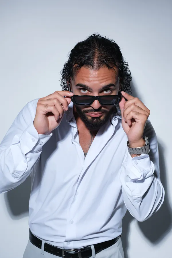 Ajay Ramos in a white shirt, lowering his sunglasses