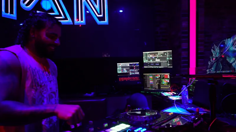 Ajay Ramos DJing a Latin night in a neon-lit booth