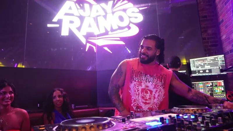 Ajay Ramos DJing under a giant AJAY RAMOS screen