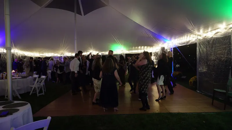A packed wedding dance floor under a lit tent, DJ'd by Ajay Ramos
